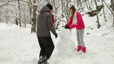 寒假在雪林里，一对少年夫妇<strong>正在</strong>堆雪人